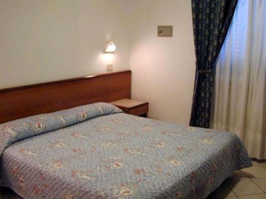 a bedroom with a bed with a blue comforter and a window at Hotel Astoria in Viareggio