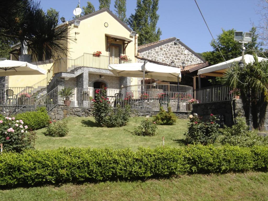 een huis met een tuin met struiken en parasols bij Ai Vecchi Crateri in SantʼAlfio