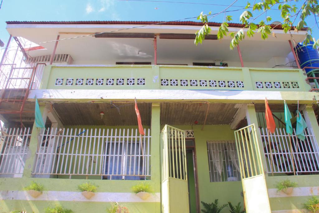 a green house with white doors and a balcony at Casaoro Homestay in Puerto Princesa City