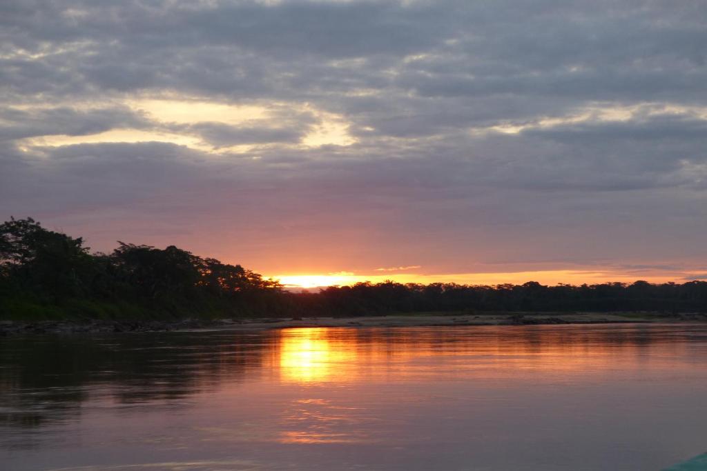 a sunset over a body of water with trees at Tambopata River in Puerto Maldonado
