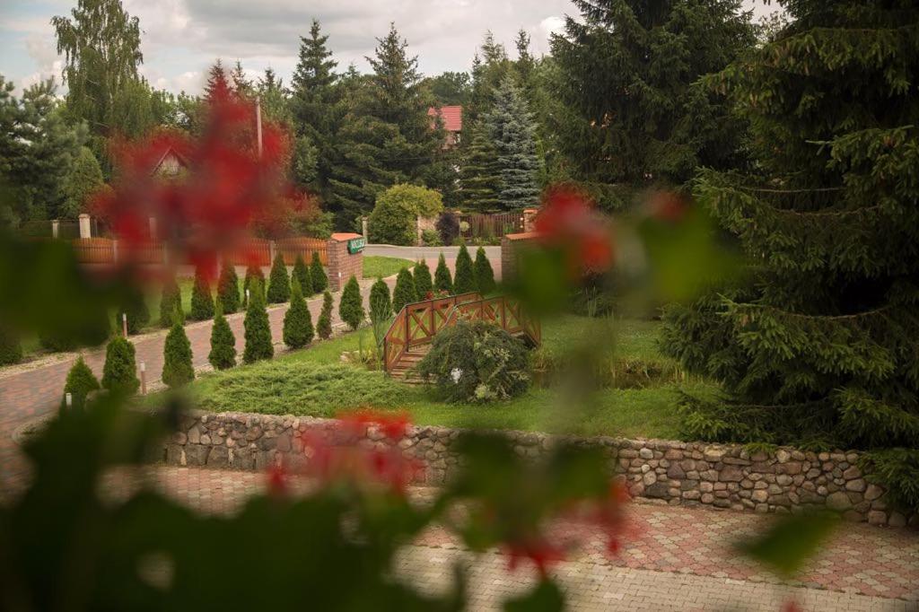 un jardín con una valla de piedra y flores rojas en Noclegi Ciesiul, en Orneta