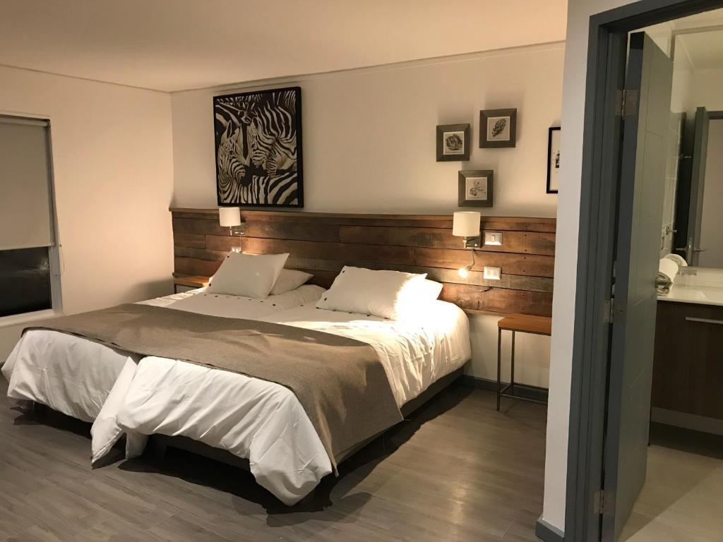 1 dormitorio con 1 cama grande y cabecero de madera en Fresia Suite, en Pucón