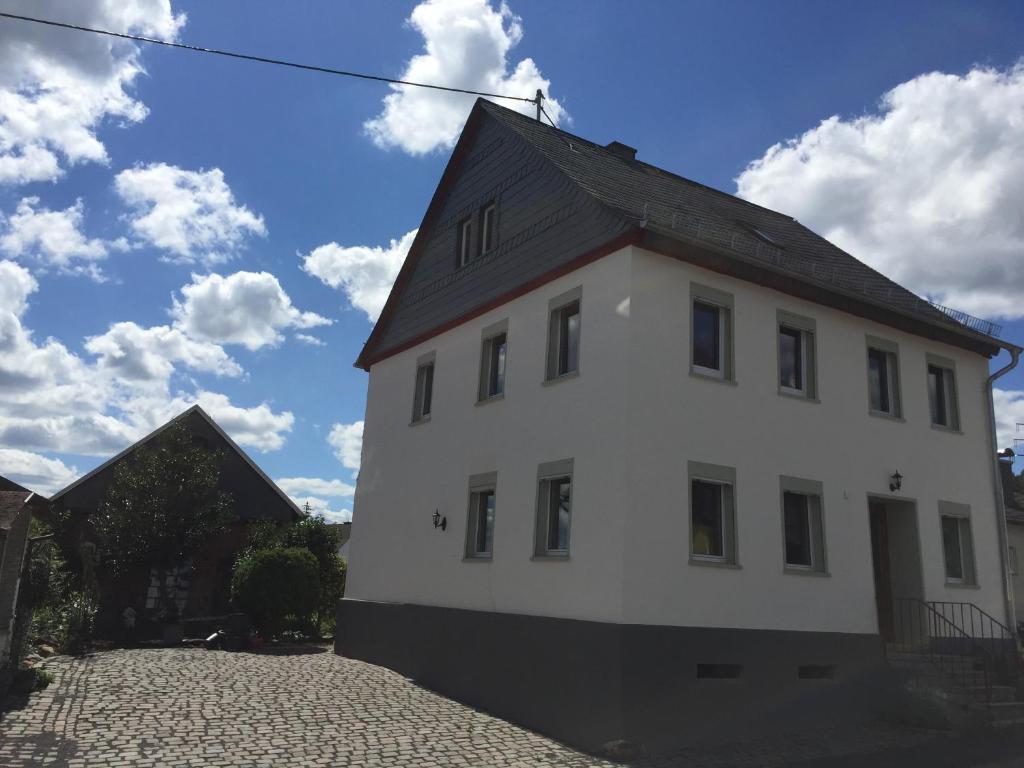 um edifício branco com um telhado preto em 4-Sterne Ferienhaus Achat-Alm mit E-Ladestation em Vollmersbach