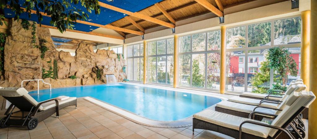 a swimming pool in a house with a rock wall at Hotel Brimer in Grundhof