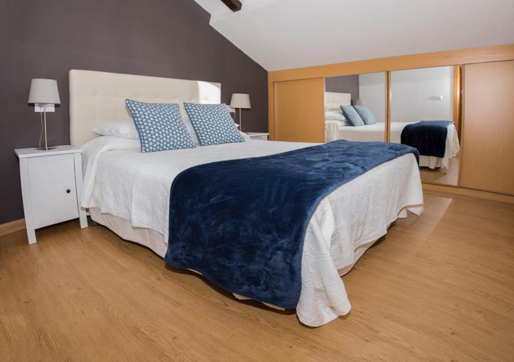 リャネスにあるApartamentos LLANES & GOLFのベッドルーム(青い枕の大型ベッド1台付)