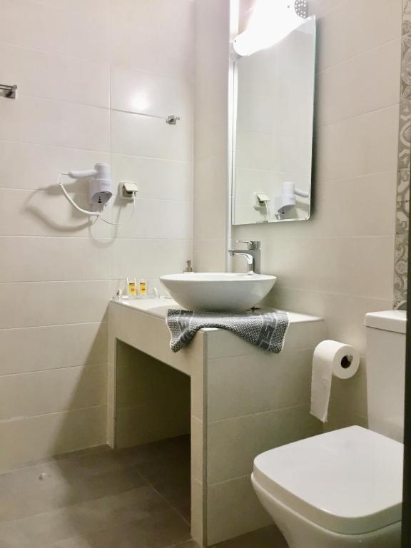 a bathroom with a sink and a toilet and a mirror at Platanos Rooms in Anopoli Sfakion