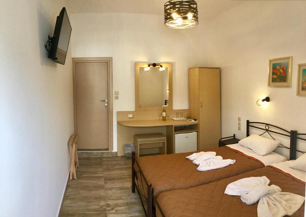 a room with two beds and a bathroom with a sink at Platanos Rooms in Anopoli Sfakion
