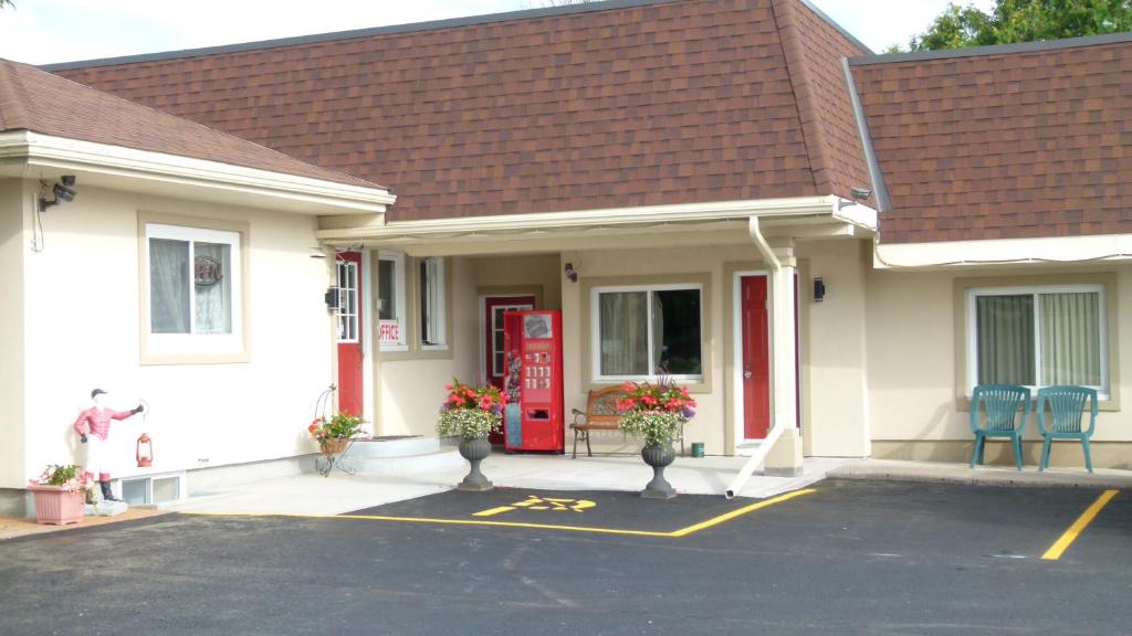 a house with a red door and chairs in a parking lot at Country Squire Motel in Arnprior