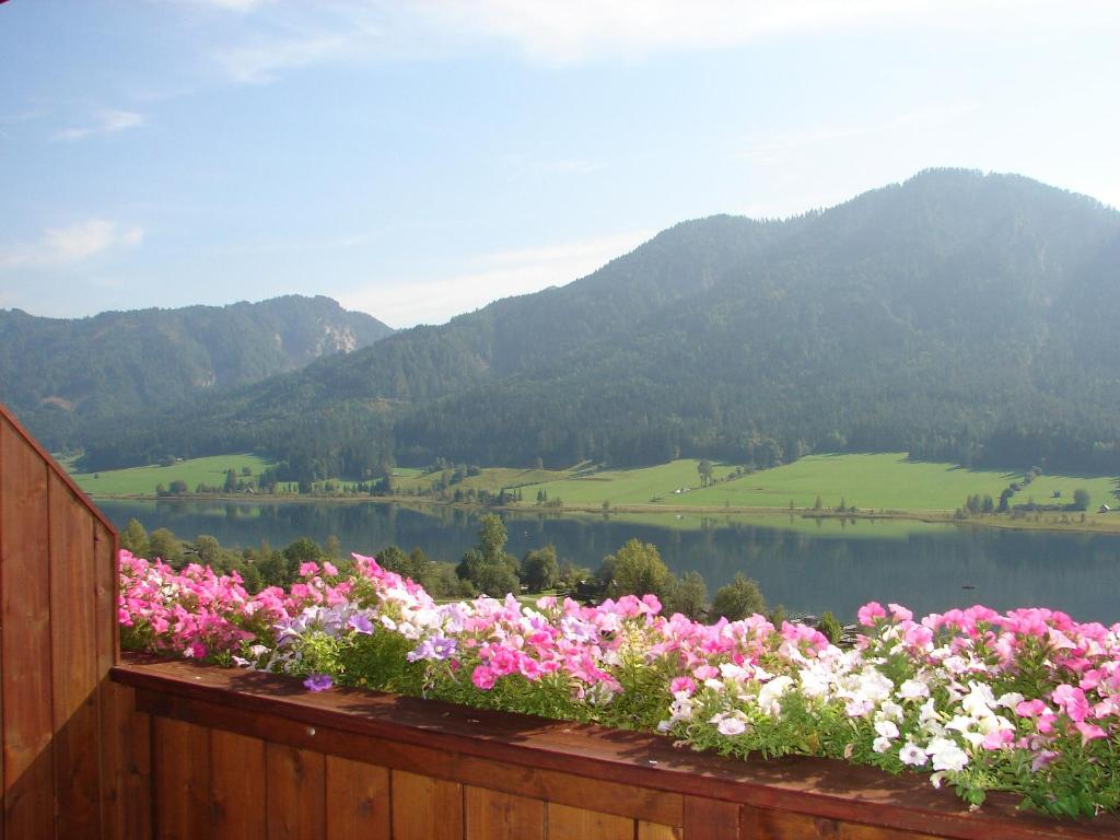 a bunch of flowers on a fence near a lake at Ferienwohnungen Plattner in Weissensee