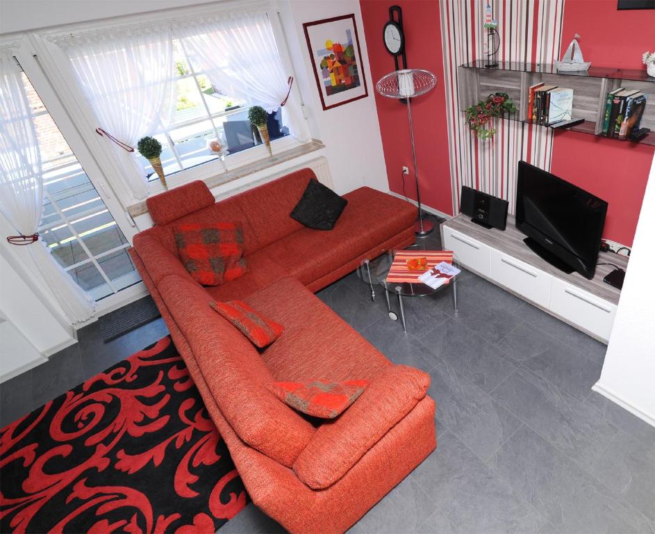 グレートジールにあるFerienwohnung Sonnenkieker Greetsielのリビングルーム(赤いソファ、テレビ付)