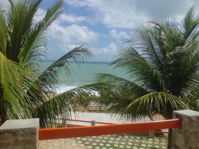 uma vista para uma praia com palmeiras e para o oceano em Chalemar Hotel Pousada em Baía Formosa