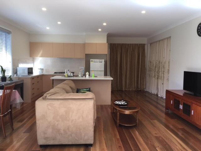 a living room with a couch and a kitchen at B2 Brand new home in Mitcham