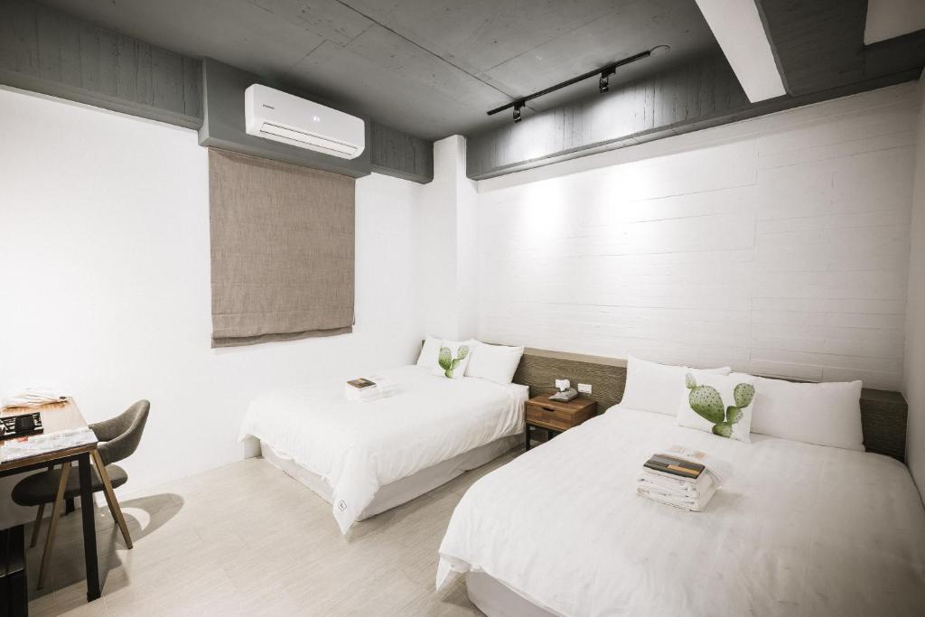 a bedroom with two beds and a desk and a window at Tiin Tinn - Rivershore B&B in Taitung City