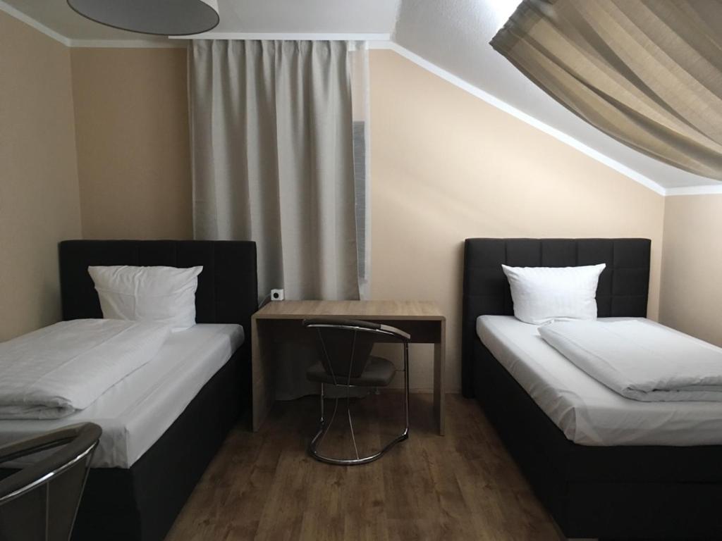 a room with two beds and a table and a chair at Hotel-Residenz Oberurseler Hof in Oberursel