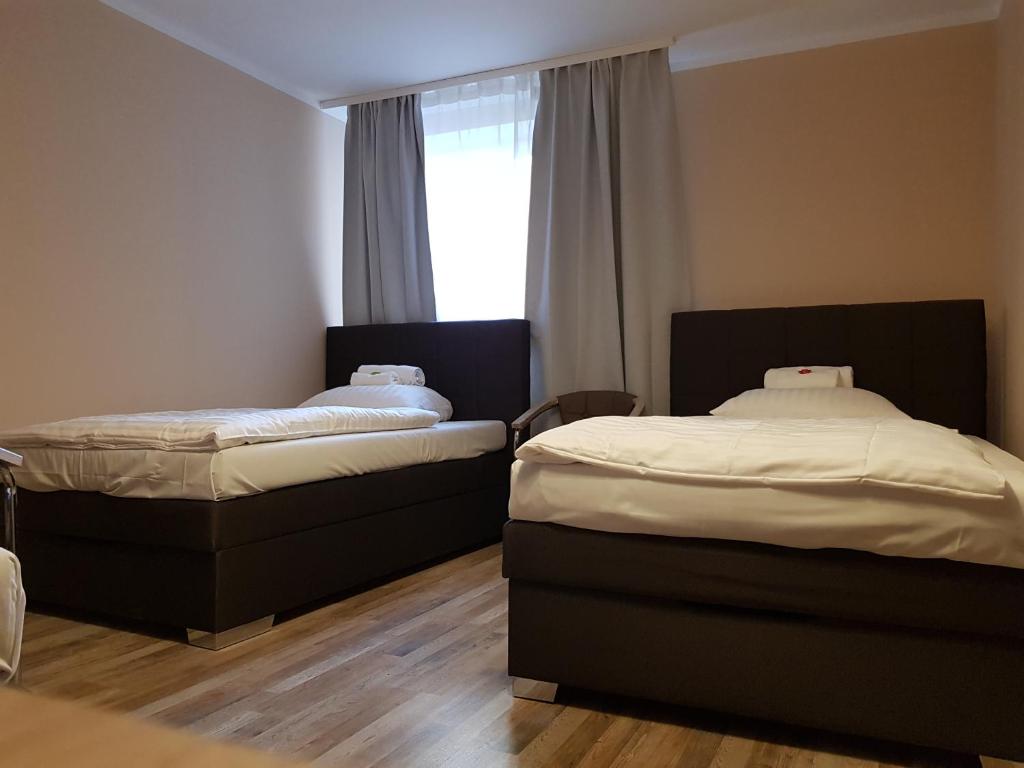 two beds in a room with a window at Hotel-Residenz Oberurseler Hof in Oberursel