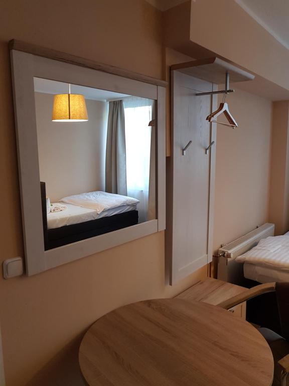 a room with a mirror with a bed and a table at Hotel-Residenz Oberurseler Hof in Oberursel