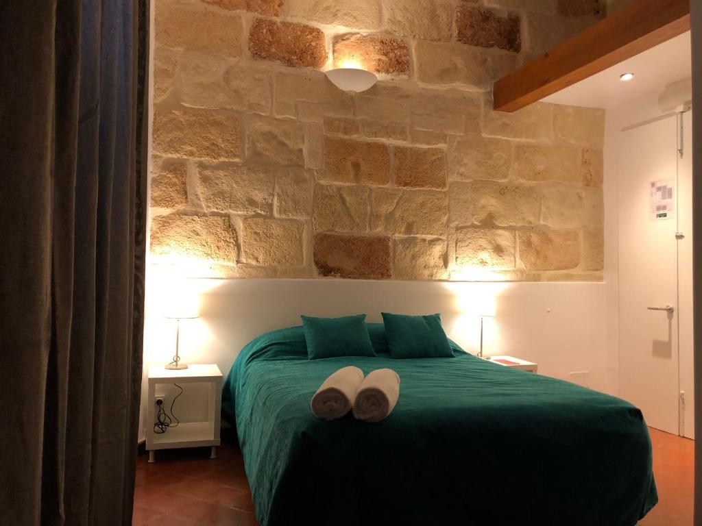 a bedroom with a green bed with two towels on it at Hostel Menorca in Ciutadella