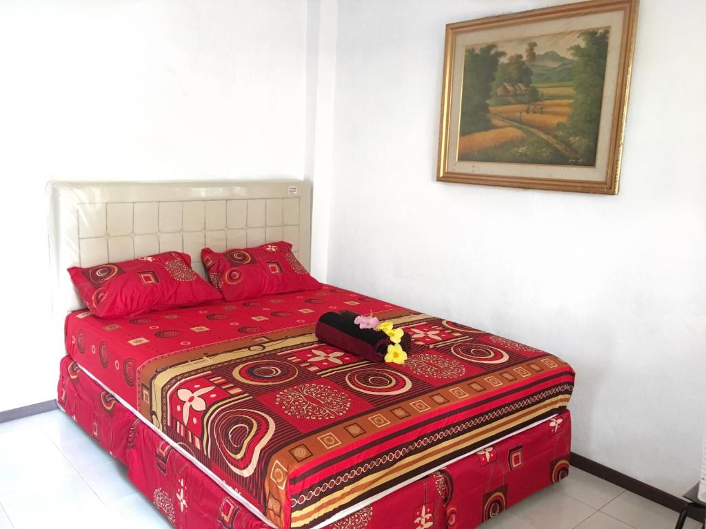 ein rotes Bett in einem Zimmer mit einem Bild an der Wand in der Unterkunft Indekost Bogor in Bogor