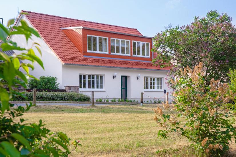 ein weißes Haus mit einem orangenen Dach und einem Hof in der Unterkunft Pension am Werbellinkanal in Eichhorst