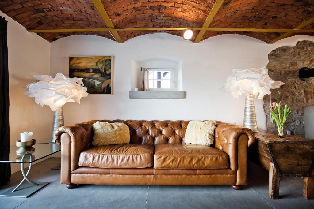 a brown leather couch in a living room with two lamps at Hossies Hof - Luxus Ferienwohnung Alter Stall in Bertsdorf