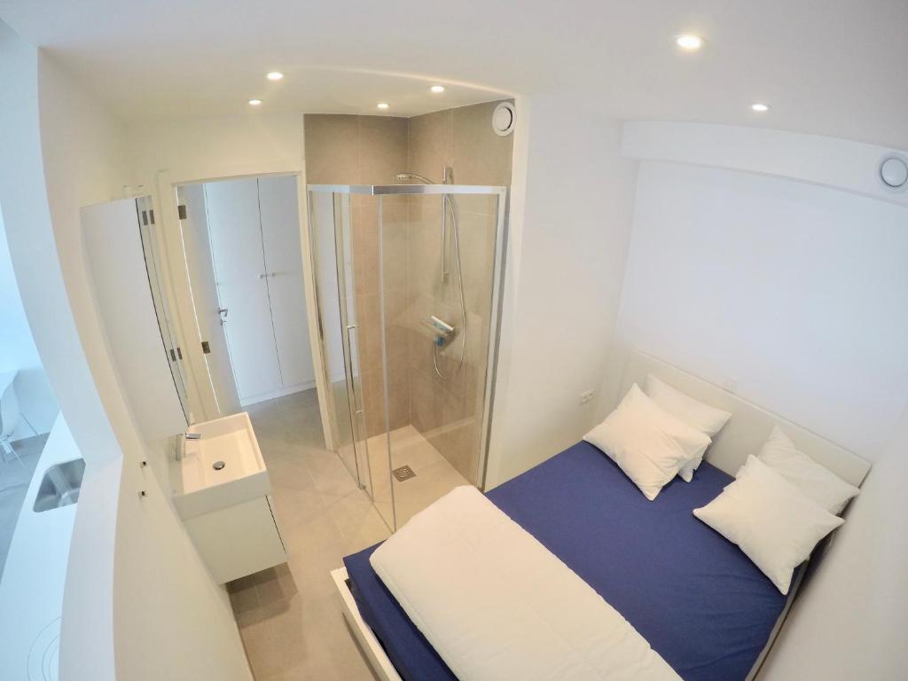 a small bedroom with a shower and a bed at Seanest - North Sea Stays in De Haan