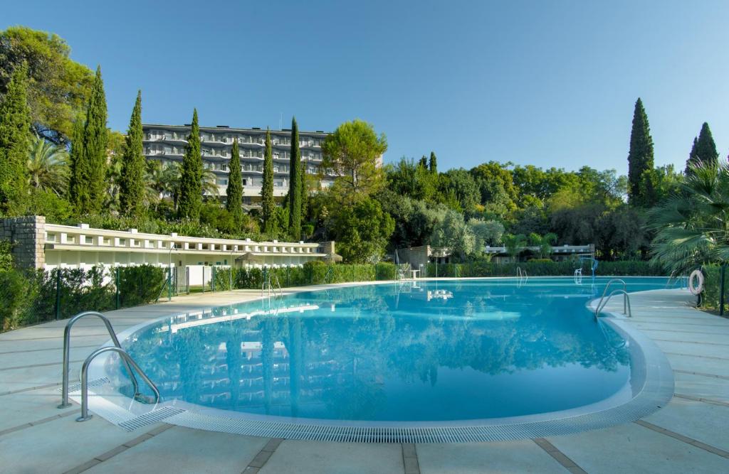 Una gran piscina con un edificio al fondo. en Parador de Cordoba, en Córdoba