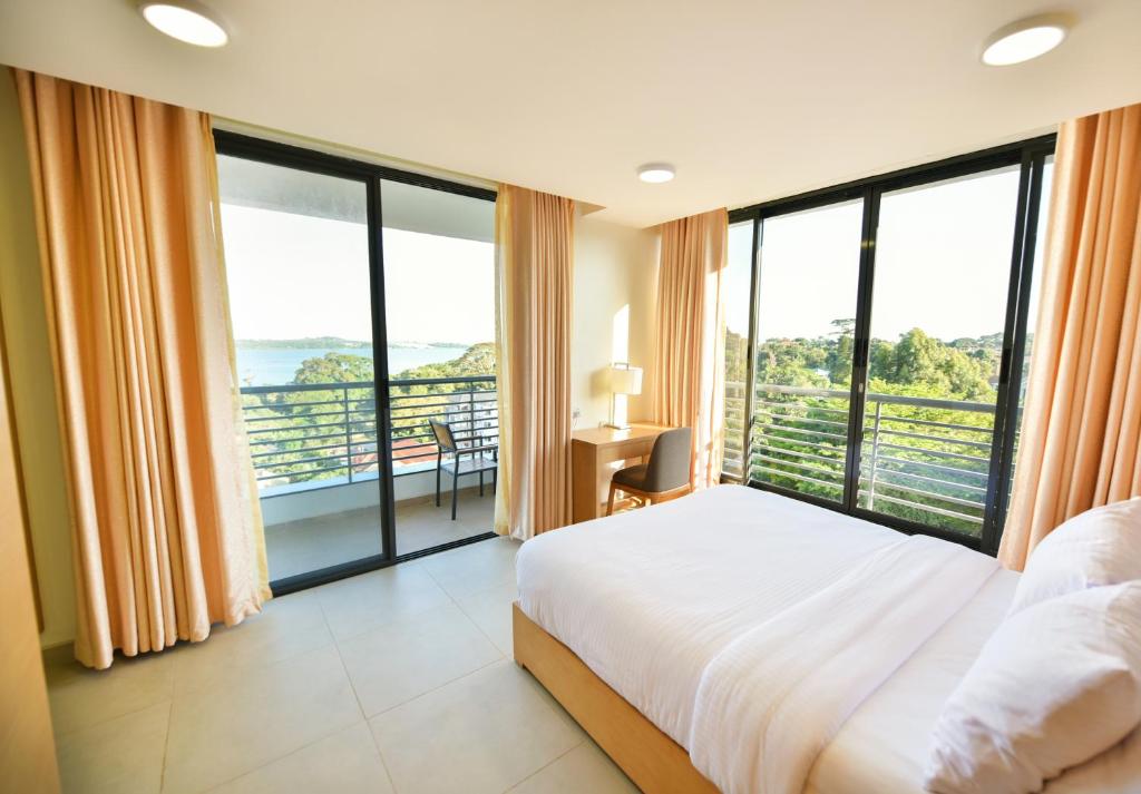 a bedroom with a large bed and large windows at K Hotels Entebbe in Entebbe