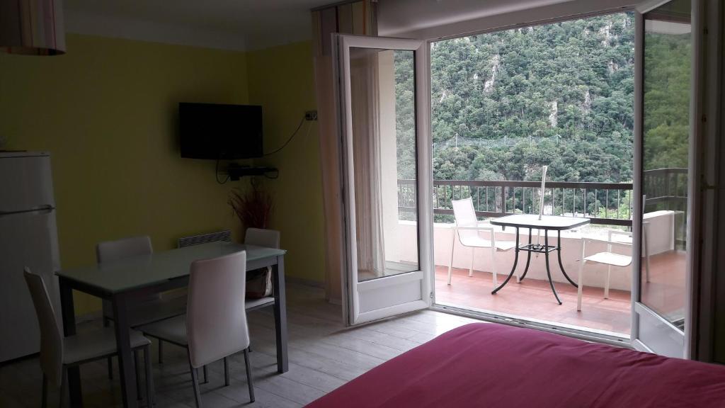 a room with a table and a dining room with a balcony at Studio couleur gai in Amélie-les-Bains-Palalda