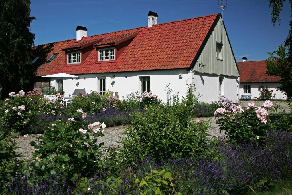 uma casa branca com um telhado vermelho e algumas flores em Stenrosgården em Kivik