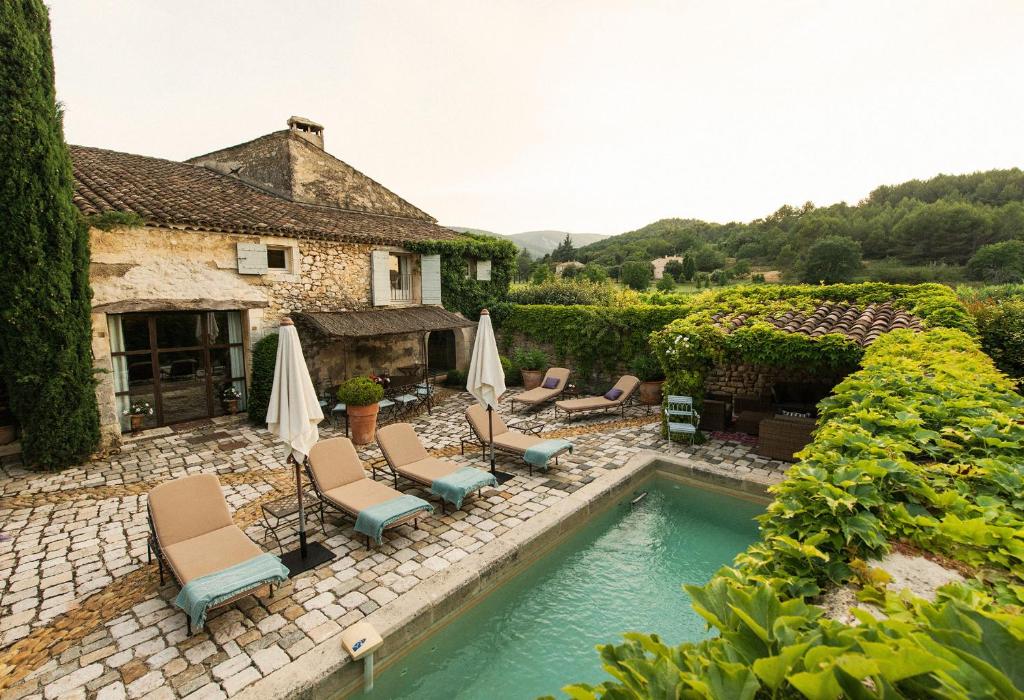 a house with a swimming pool with chairs and umbrellas at Villa Grenache, La Bastide de Marie, Villa avec services in Ménerbes