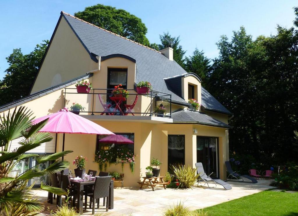 a house with a table and an umbrella in front of it at Jardin du Levant in Combourg
