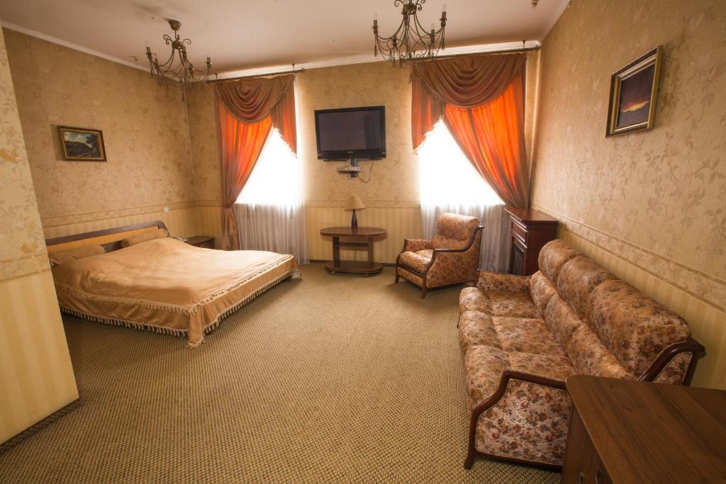 um quarto com um sofá, uma cama e uma televisão em Magnat Lux Hotel em Chernivtsi