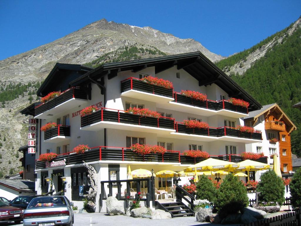 a building with flowers on the balconies in front of a mountain at Hotel Restaurant Mattmarkblick in Saas-Almagell