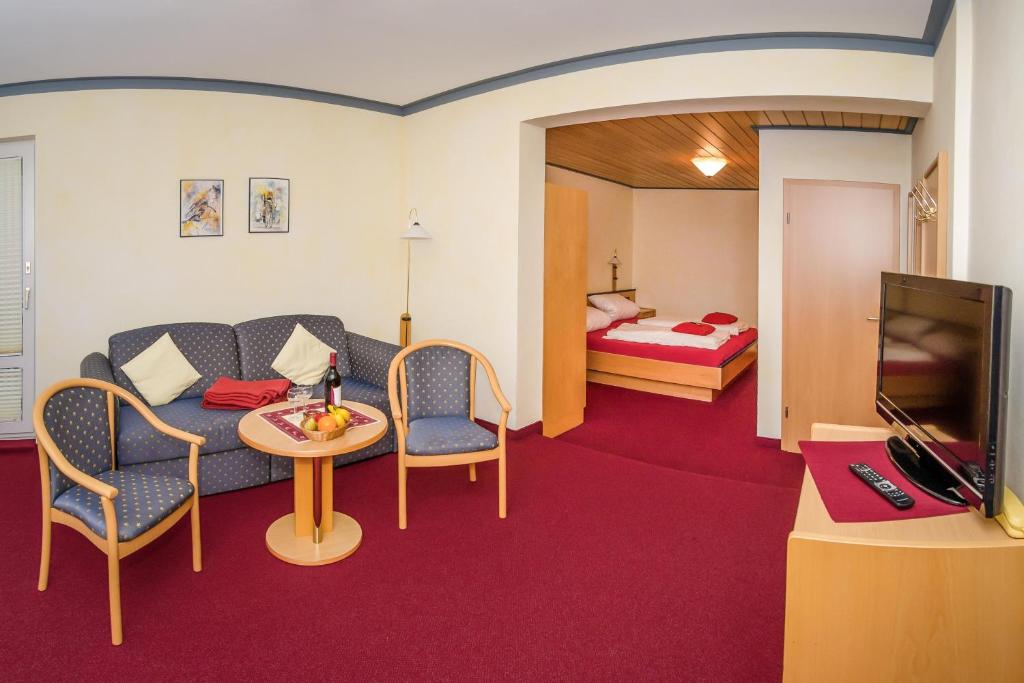 a room with a couch and a table and a bed at Schröder's Hotelpension in Willingen