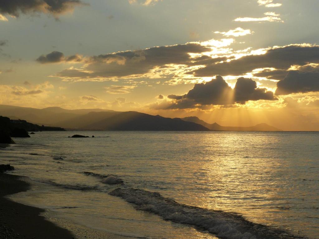 a sunset on the beach with the sun setting at Ierapetra La Luna Blu in Ferma