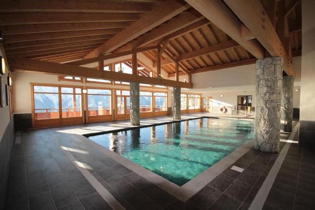 a large swimming pool in a building with windows at LES SAISIES - LA PERLE DES ALPES in Les Saisies