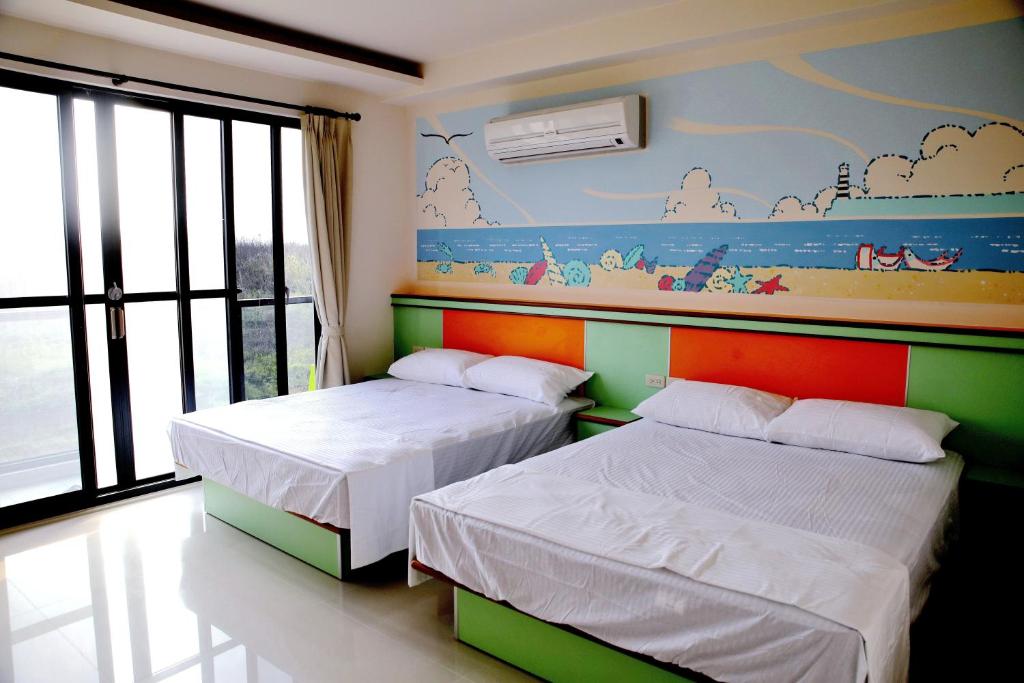 duas camas num quarto com um mural na parede em Caibei Homestay em Magong