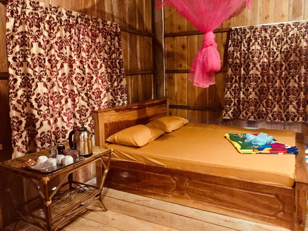瓜隆岛PSK VIMEAN KOH RONG Guesthouse的一间卧室配有一张带粉红色窗帘的木床