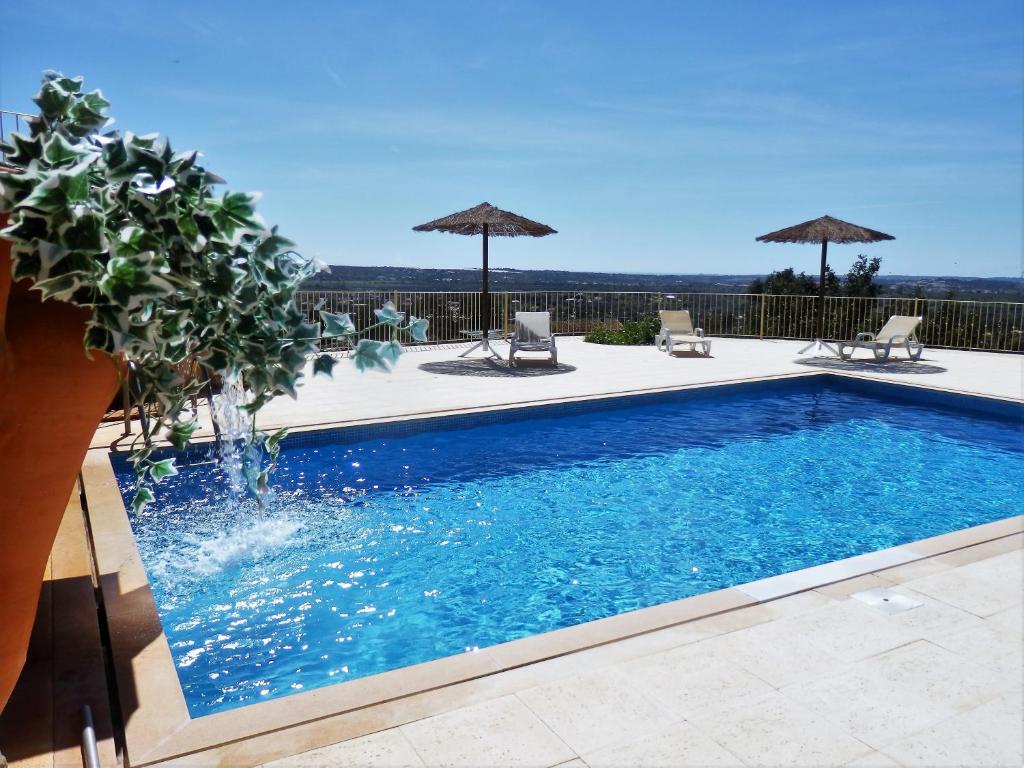 a swimming pool with chairs and umbrellas at Quinta Sabaudia in Gateiras