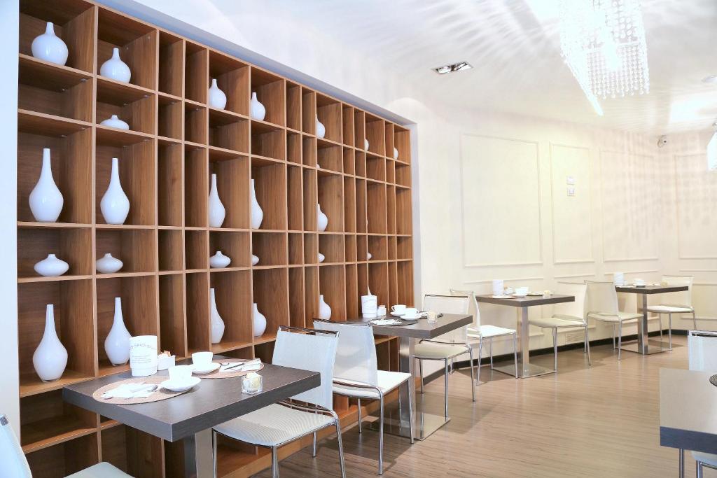 a dining room with tables and white vases on a wall at Hotel Carla in Levanto