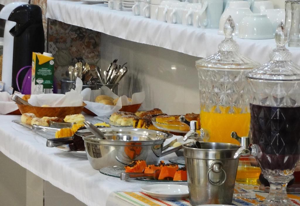 a table with a buffet of food and orange juice at Hotel Monte Carlo Uberlândia in Uberlândia
