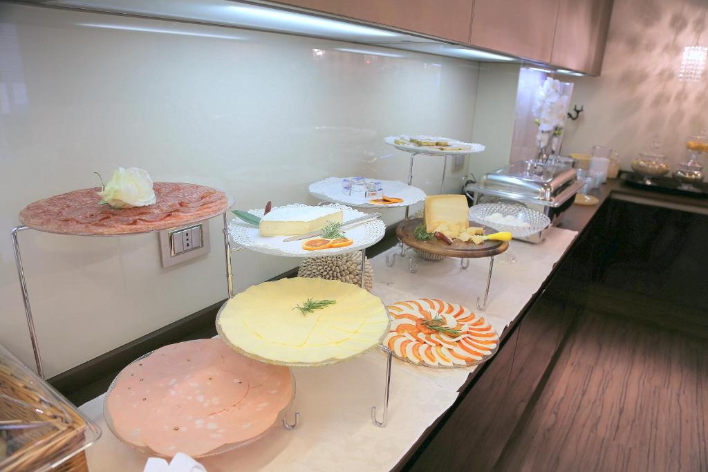a kitchen with several tables with different types of food at Hotel Carla in Levanto