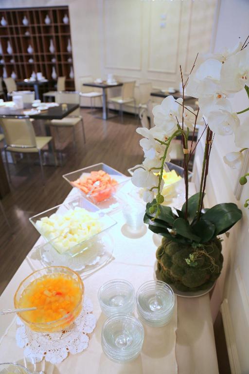 a table topped with bowls of food and flowers at Hotel Carla in Levanto