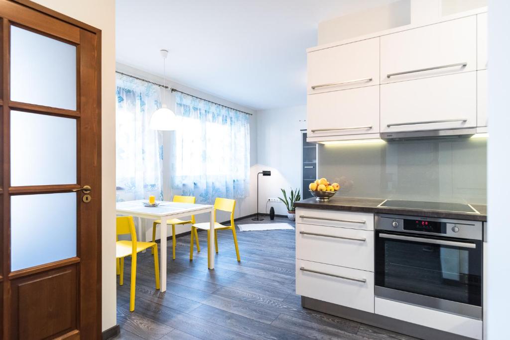 uma cozinha com armários brancos e uma mesa com cadeiras amarelas em Alma Apartman em Salgótarján