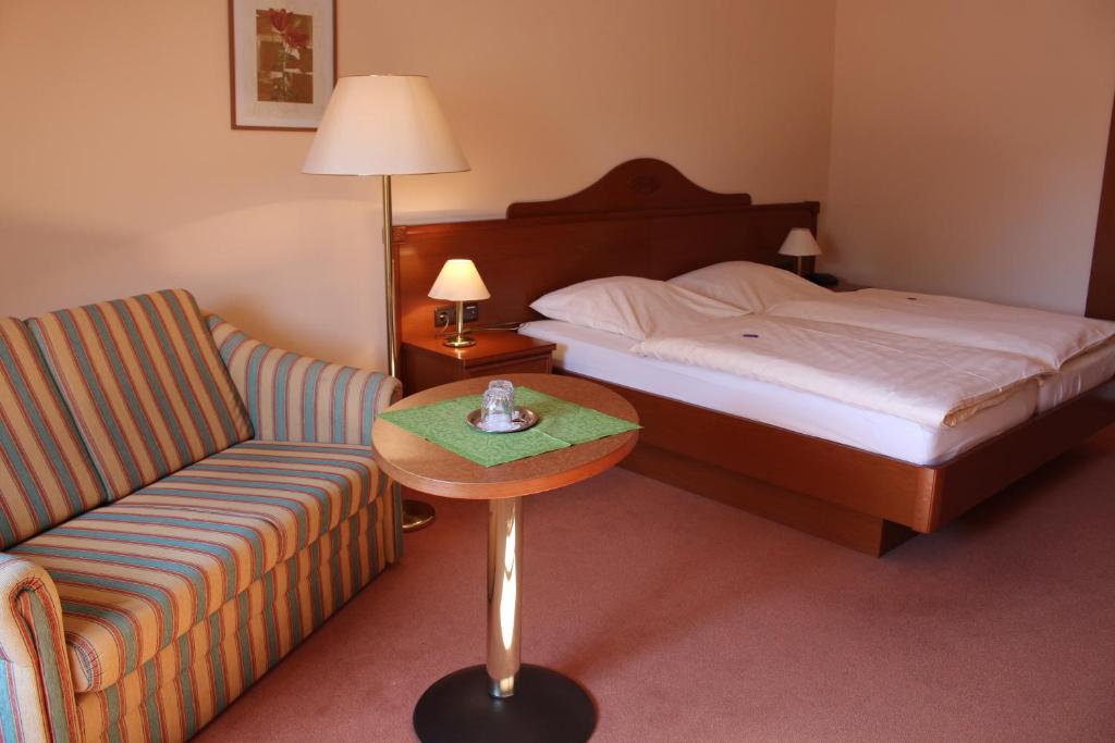 ein Hotelzimmer mit einem Bett, einem Stuhl und einem Tisch in der Unterkunft Zur Querensteder Mühle in Bad Zwischenahn