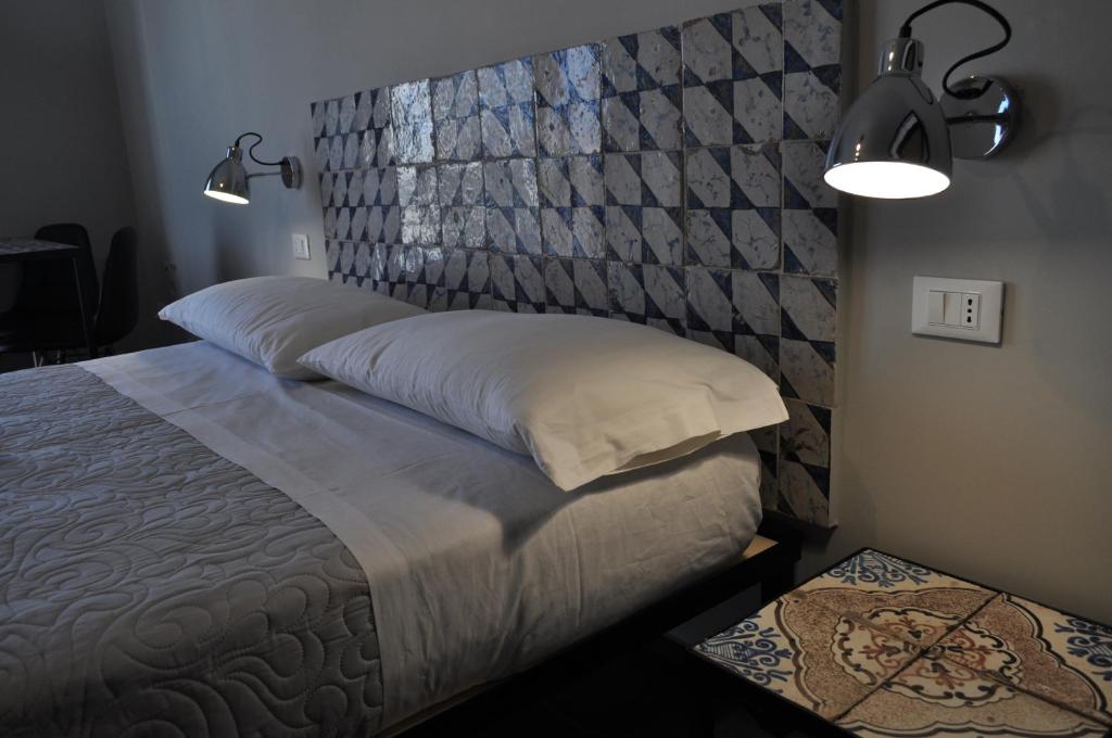 a bedroom with a bed with a headboard and lights at Casanetina in Noto