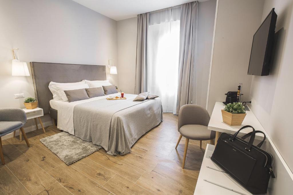 a bedroom with a bed and two chairs and a television at Colonna Luxury Suites in Rome