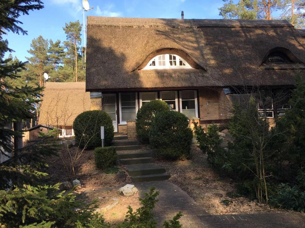 a house with a thatched roof and stairs in front at Ferienhaus Duenenwald 1 _LANG in Ostseebad Karlshagen