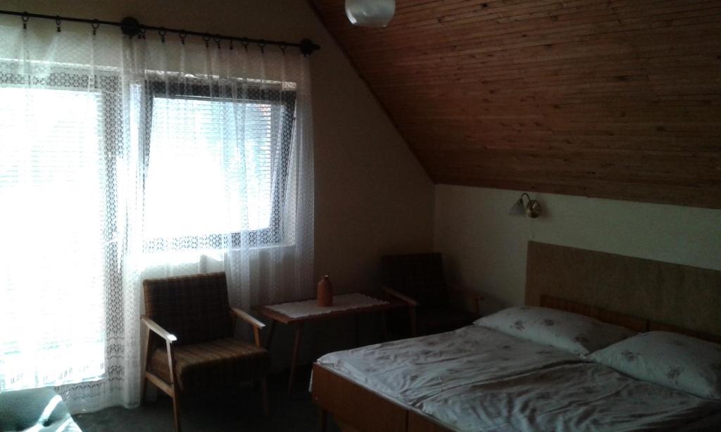 1 dormitorio con 1 cama, 1 silla y 1 ventana en Hutter Vendégház en Szántód