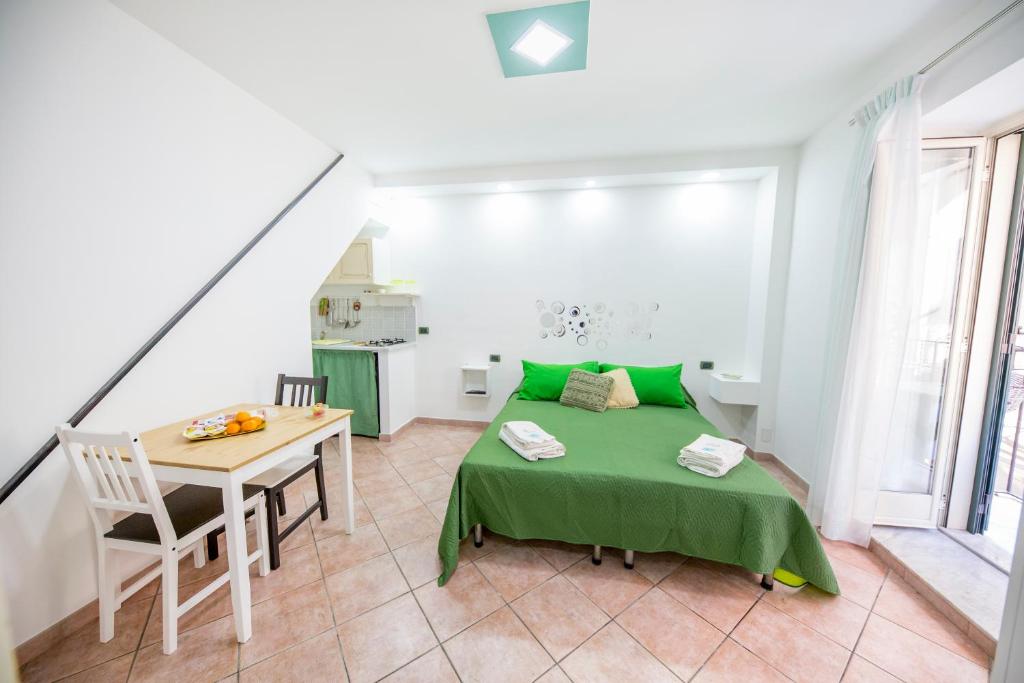 ein kleines Zimmer mit einem Tisch und einem grünen Bett in der Unterkunft Casa Smeraldo in Cefalú